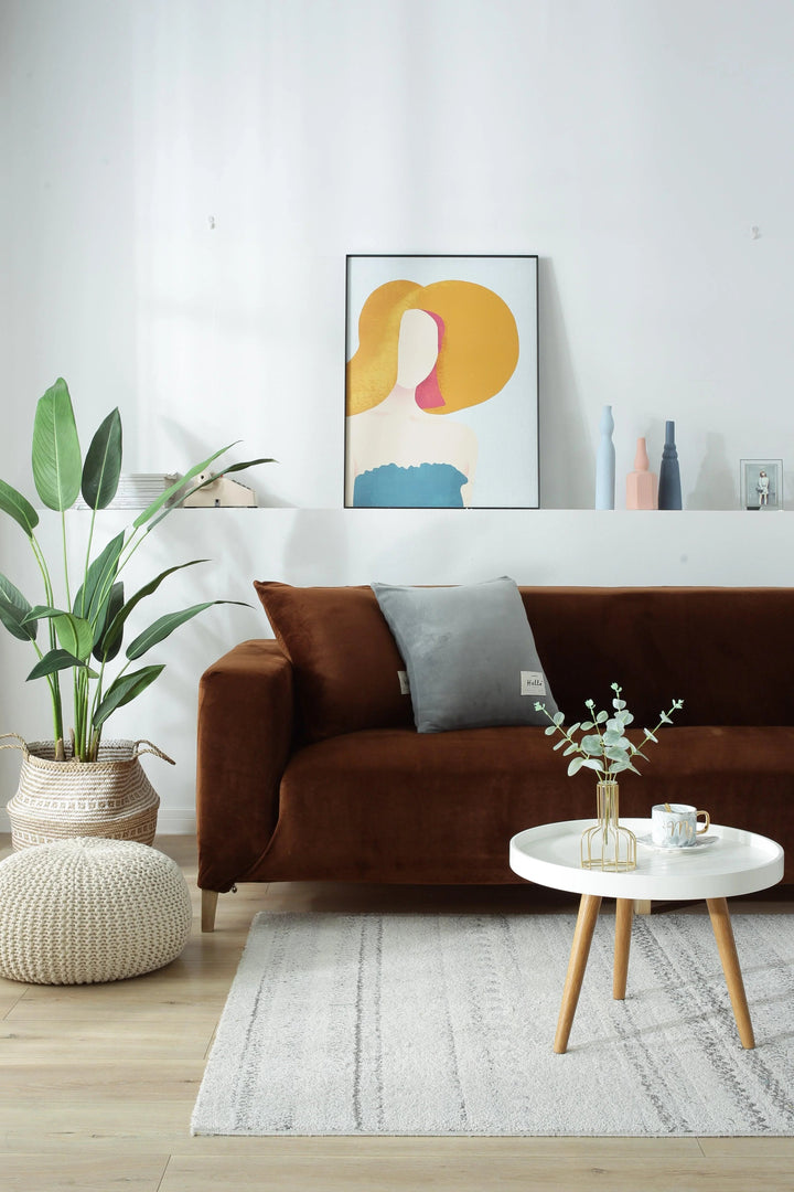 Brown velvet couch cover draped over a sofa, with decorative pillows and a plant nearby.