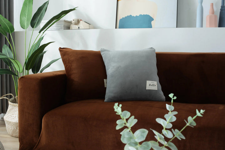 Brown velvet couch cover draped over a sofa with a grey pillow.