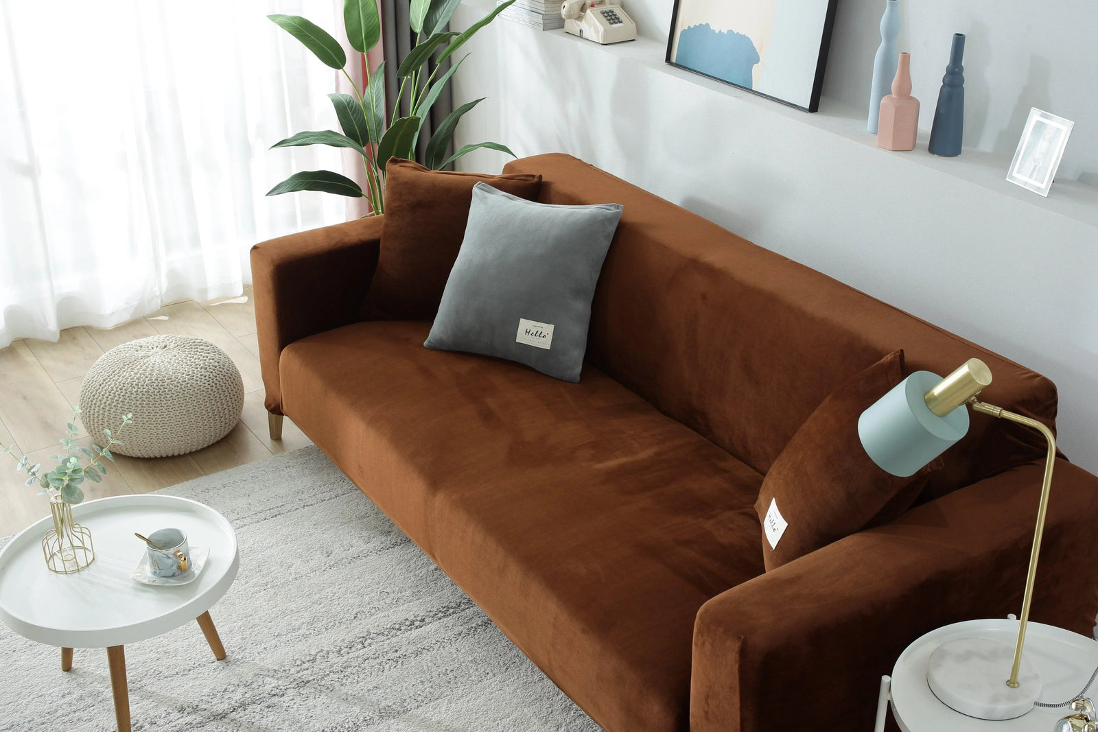 Brown velvet couch cover draped over a sofa with decorative pillows and a lamp.