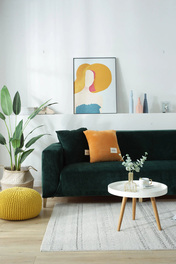 Dark green velvet couch cover on a sofa with decorative pillows and a coffee table.