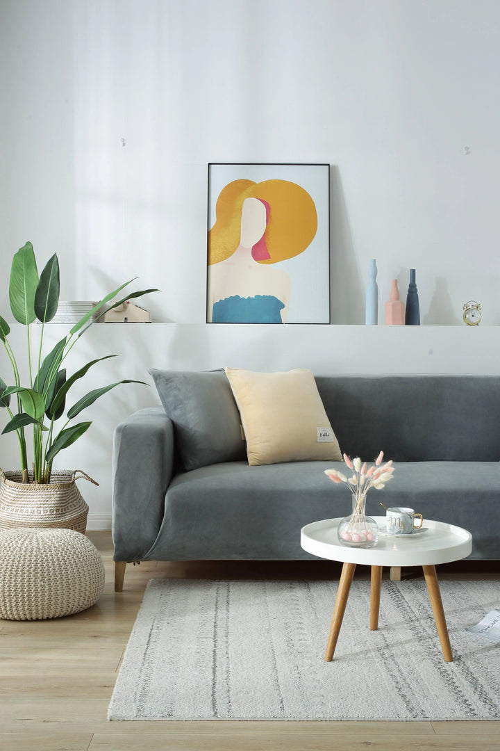 A light grey velvet couch cover is draped over a sofa, featuring a plush texture and adaptable fit.