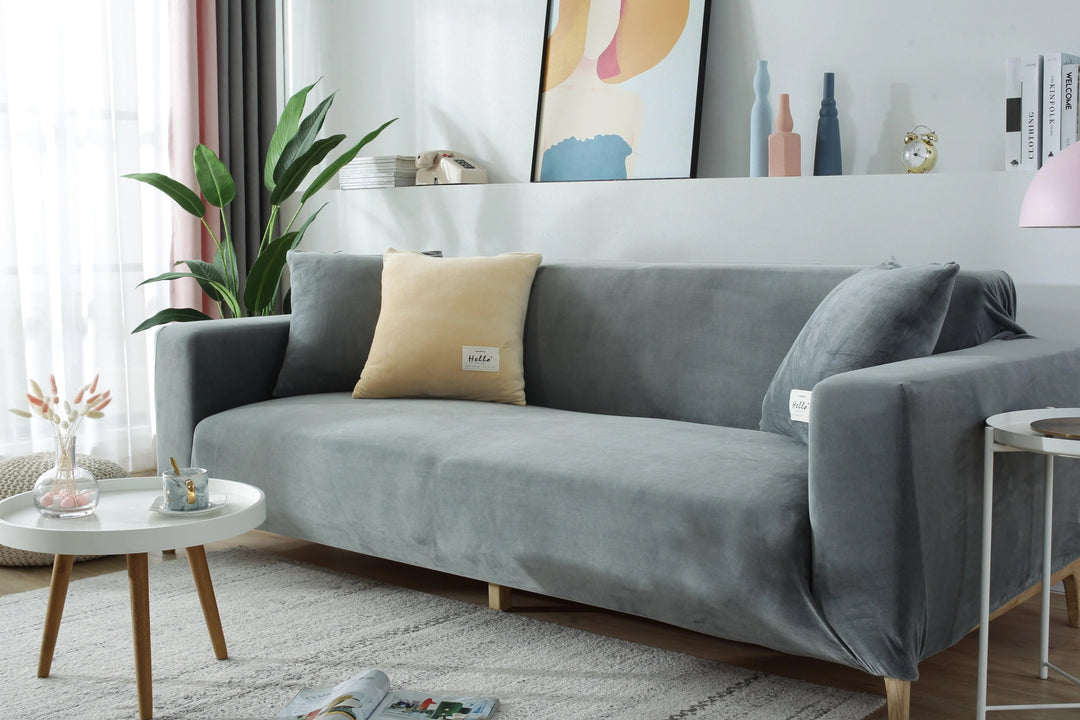 Light grey velvet couch cover draped over a sofa, with decorative pillows.