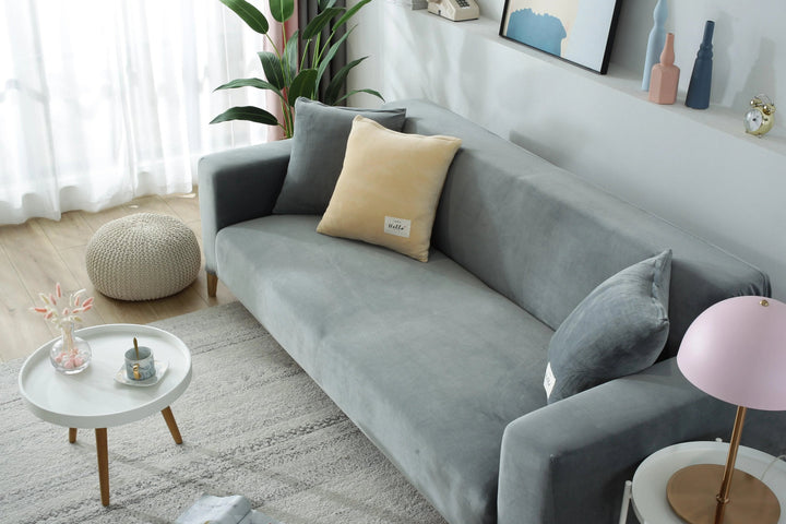 Light grey velvet couch cover draped over a sofa, with decorative pillows.