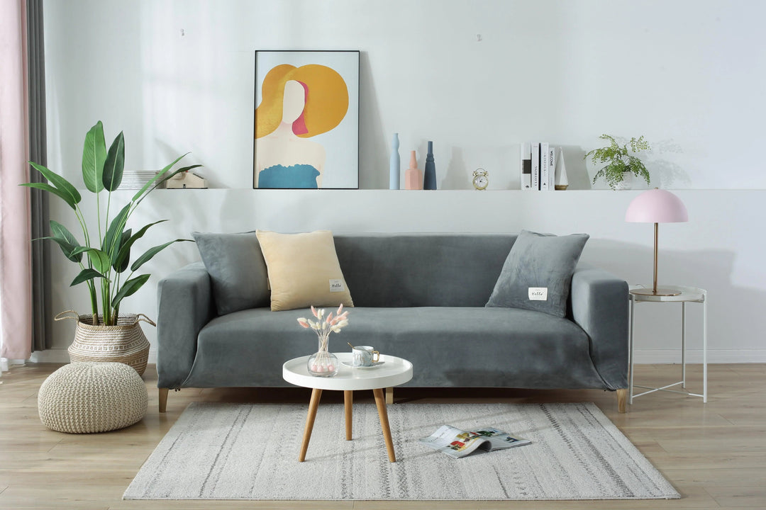 Light grey velvet couch cover on a sofa, with decorative pillows and a small table.