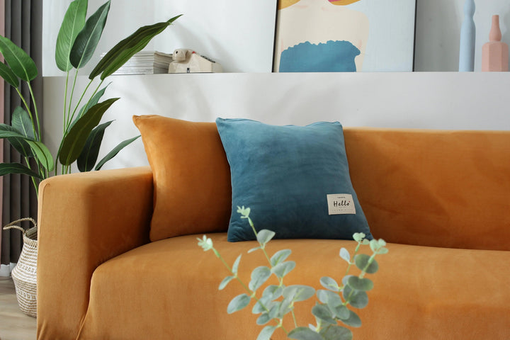 Orange velvet couch cover shown on a sofa with blue and orange pillows.