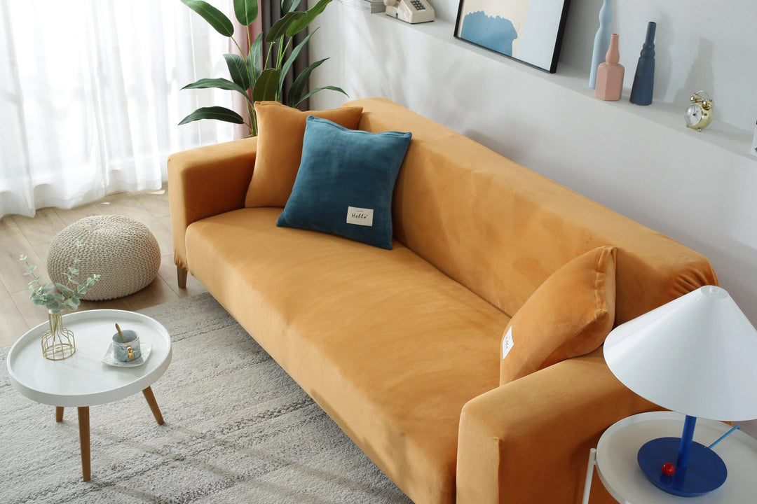Orange velvet couch cover on a sofa with teal and orange pillows.