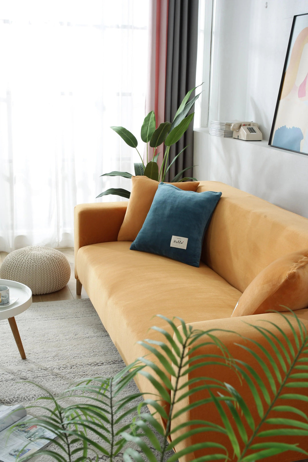 Orange velvet couch cover on a sofa with blue and orange pillows.