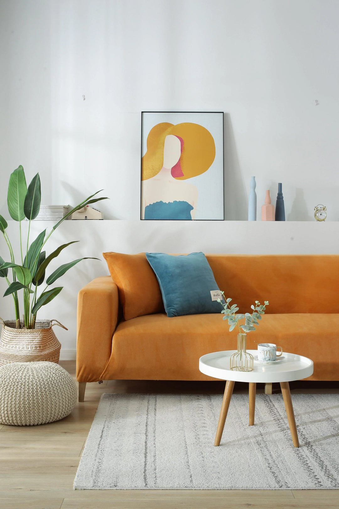 Orange velvet couch cover draped over a sofa, with a blue pillow and a small white table.