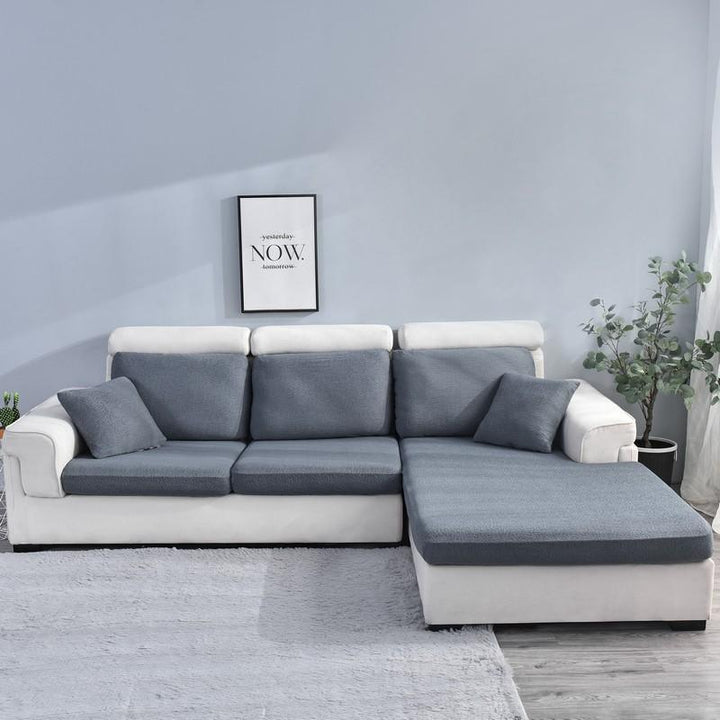 Dark grey waterproof sofa cushion cover on a sectional sofa with white upholstery.