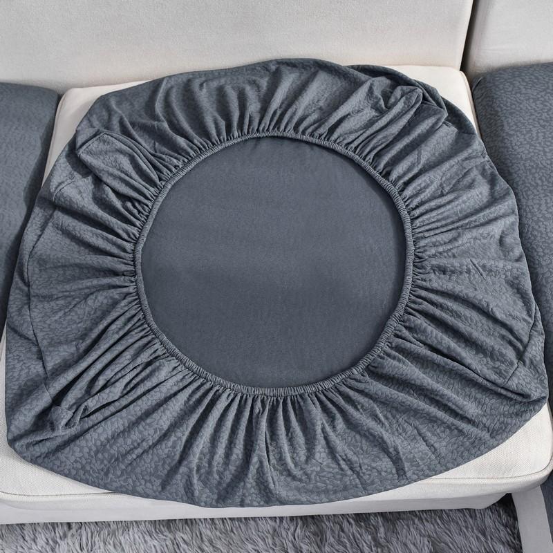 Dark grey waterproof sofa cushion cover with elasticated edges, shown on a sofa.