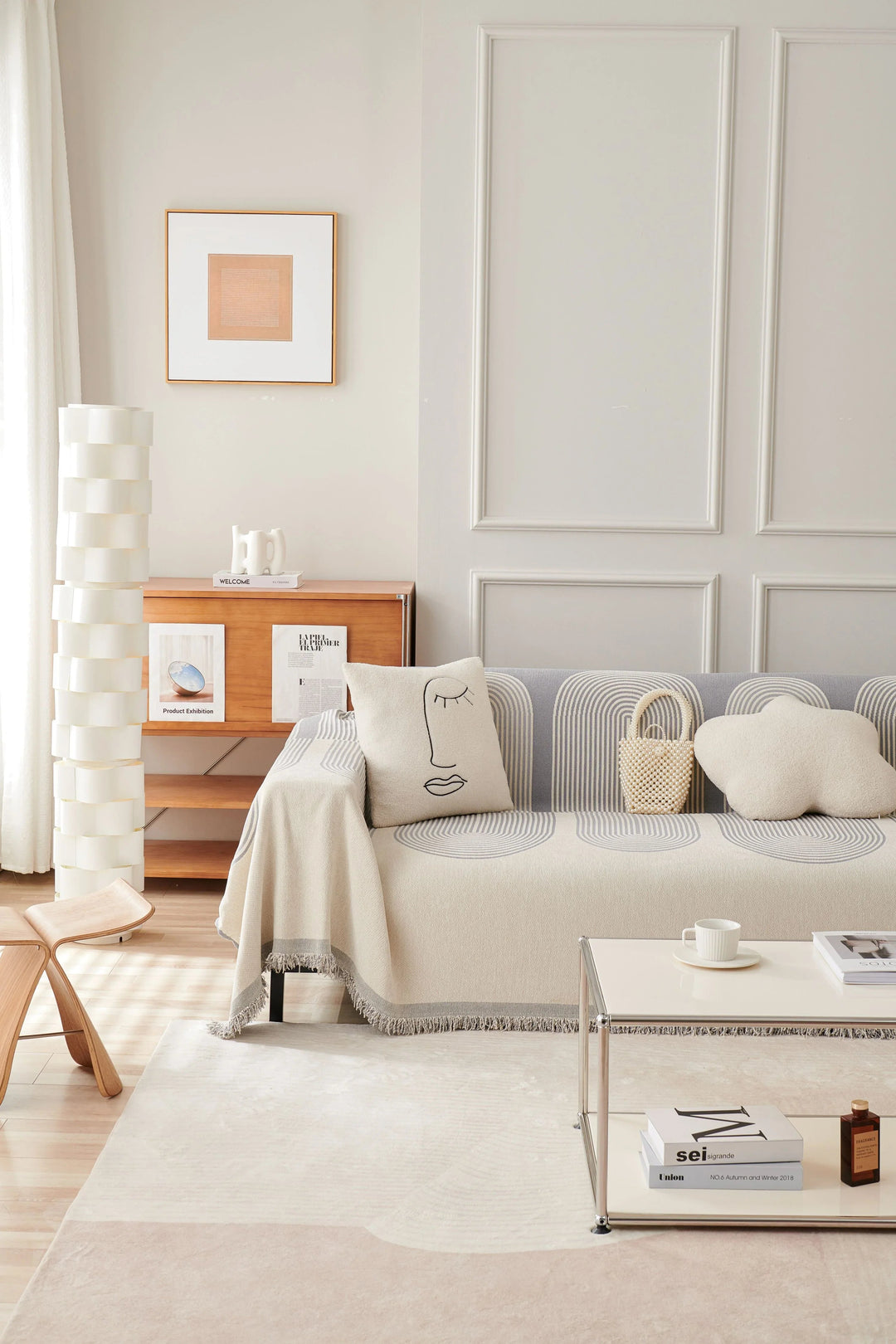 Dusty grey chenille throw blanket draped over a sofa with decorative pillows and a small woven bag.