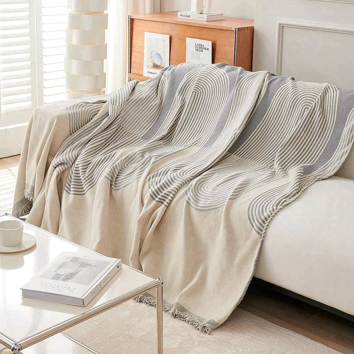 Dusty grey chenille throw blanket with a geometric pattern draped over a sofa.