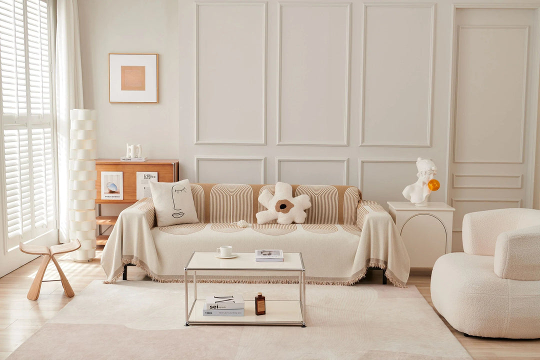 Sandy tan chenille throw blanket draped over a sofa with tassels.