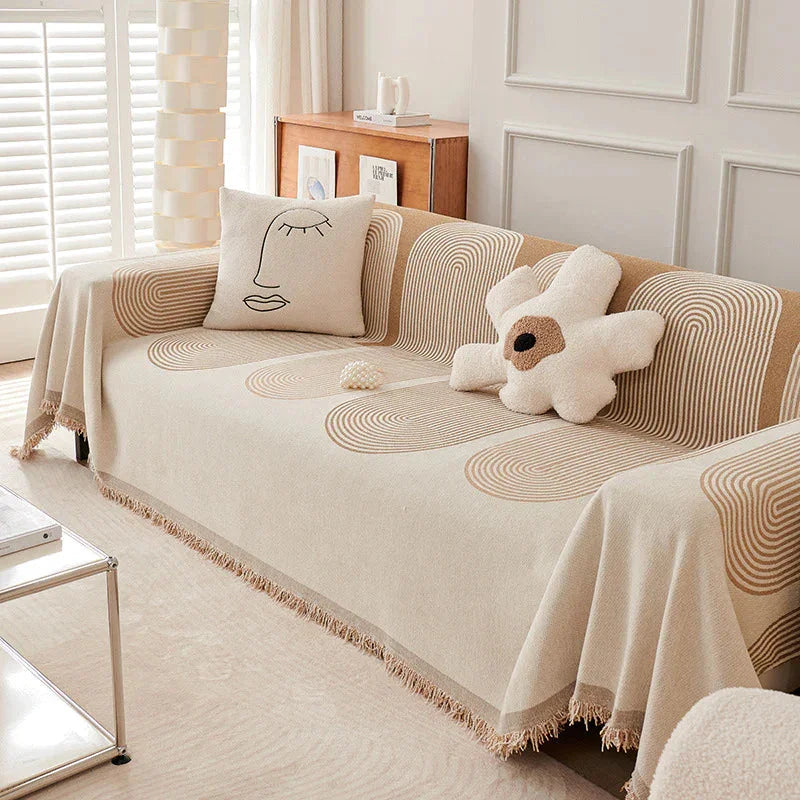 Sandy tan chenille throw blanket draped over a sofa with decorative pillows.