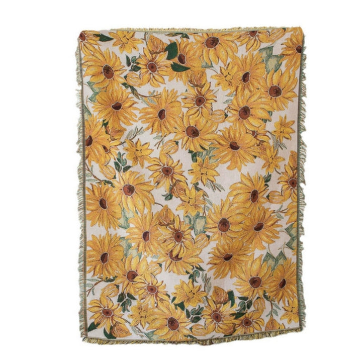 A woven blanket with a repeating pattern of yellow sunflowers on a cream background.