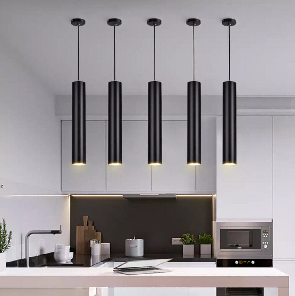 Five black tube pendant lights hanging in a modern kitchen over a counter.