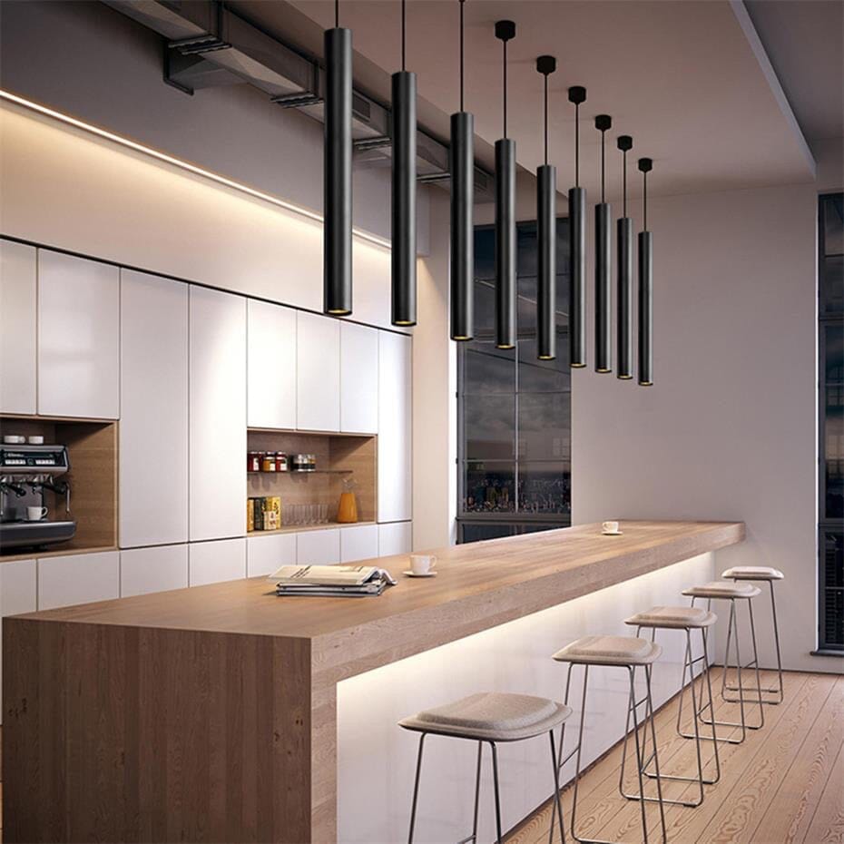 Modern black tube cluster pendant light hanging over a wooden kitchen island with stools.