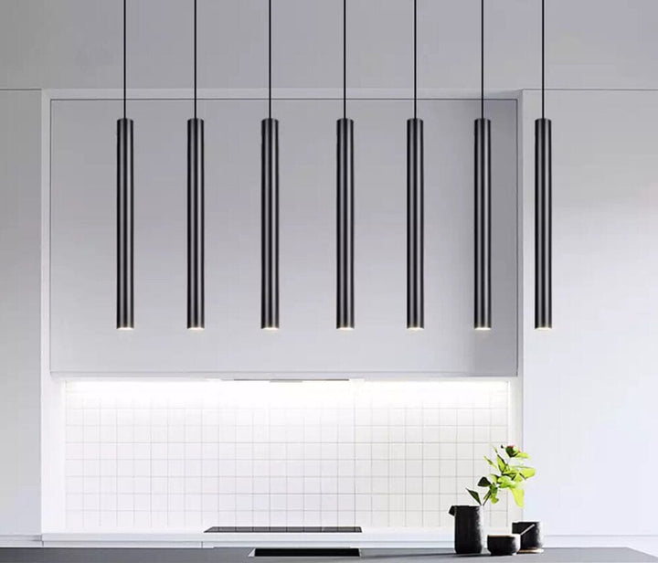Modern black tube cluster pendant light hanging over a kitchen counter.