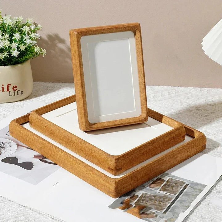 Two handcrafted solid wood photo frames with natural finish, one standing on a larger frame.